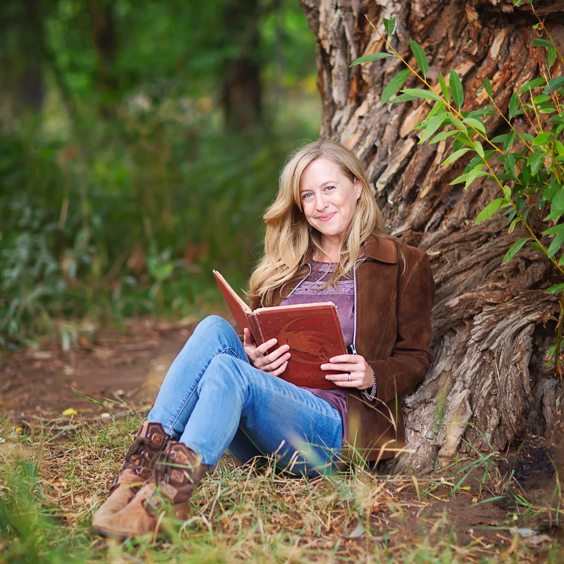 Laura smiling, holding a book under a tree