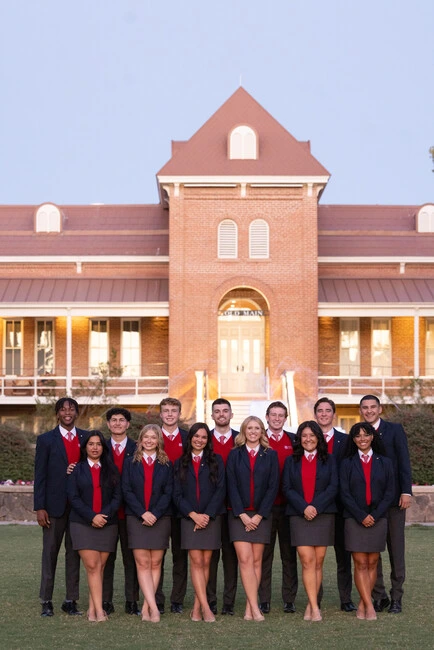 Image of a group of 6 female studets and 7 male studnets posing for group photo in front of Old Main.