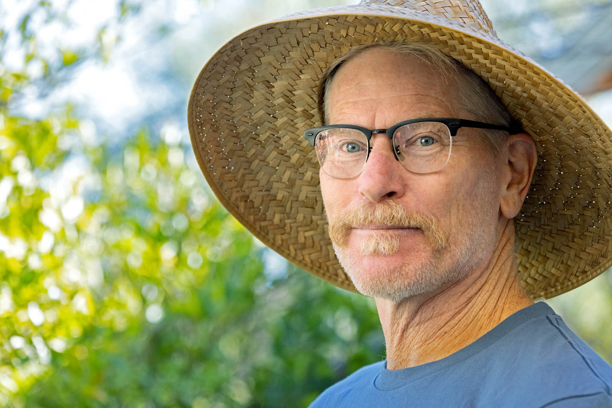 Lancaster looking at the camera, wearing a hat, in the garden 