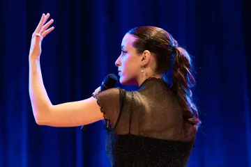 Woman gestures with microphone while singing