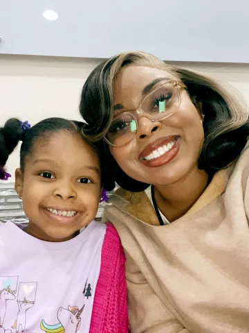 A photograph of a mother and daughter smiling next to each other