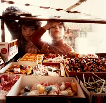 A photograph of two boys looking at candy through a glass display.