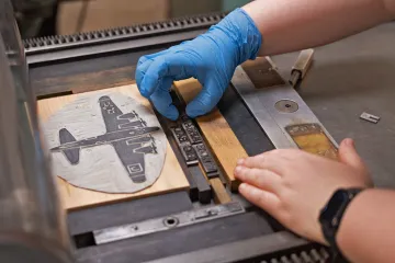 Image of person creating book art on a machine.