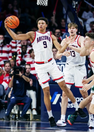 Carter Bryant grabbing a ball with his right arm in front of an audience cheering 