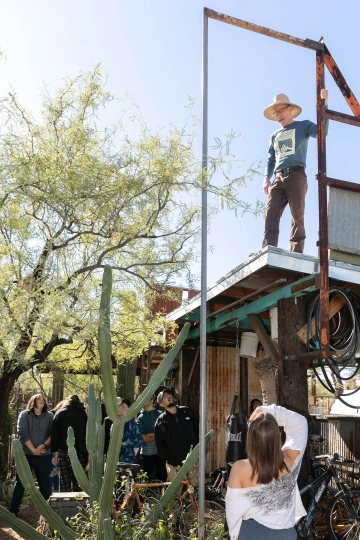 Lancaster standing on a roof while speaking with attendees