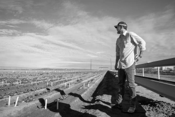 A black and white photo of William Duke Pauli looking into the distance to his fields.