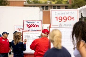 A couple filling out their name in the Class of 1980 sign-in