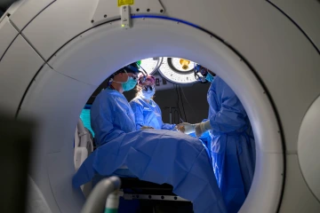 A photo of three surgeons in operating room performing a neurology surgery.