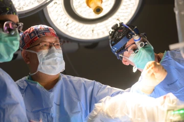 A photo of three surgeons in operating room performing a neurology surgery.