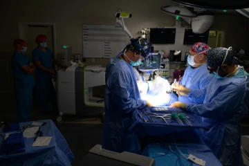 A photo of three surgeons in operating room performing a neurology surgery.