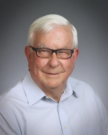 Alan smiling, wearing a white shirt and black glasses 