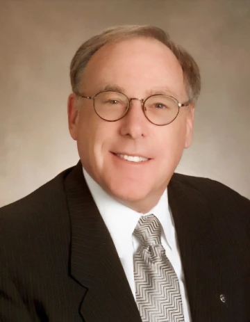 Cecil smiling while wearing a black suit and a gray tie 