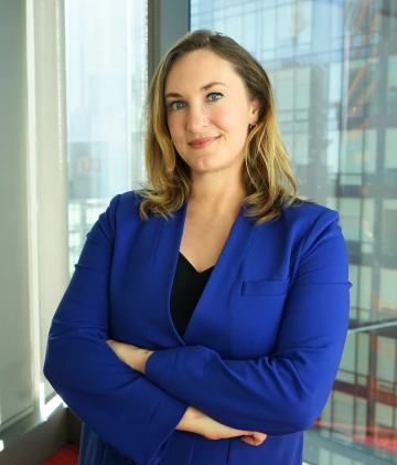 Mary Foote smiling, with her arms crossed, wearing a dark blue blazer and a black shirt 