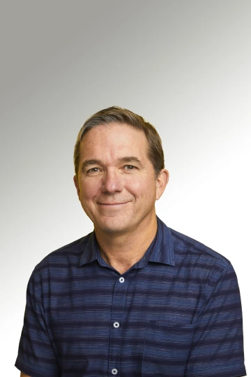 Jerry smiling, wearing a black and blue striped polo 