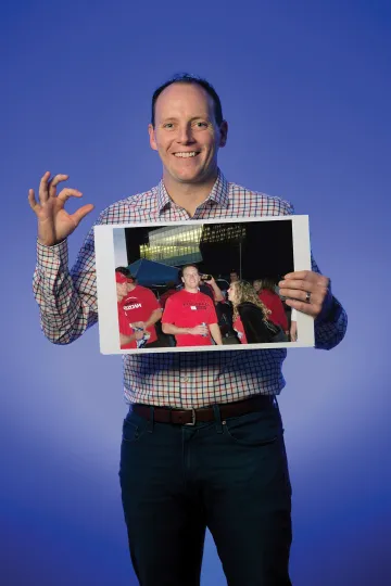 A photograph of Alex Manuel holding a photograph of his exciting college years