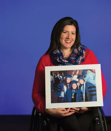 A photograph of Amanda Kraus holding a photograph from her graduation