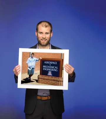 A photograph of David Hahs holding a photograph of himself in front of the Aerospace and Mechanical Engineering building