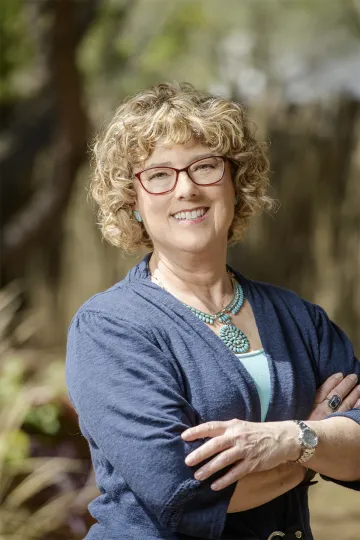 A photograph of Esther Sternberg smiling with her arms crossed