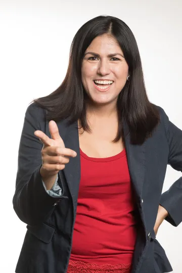 A photograph of Nancy Hernandez smiling, with her hand playfully pointed