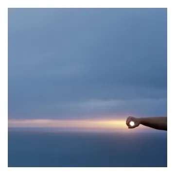 A photograph of an individual sticking their hand out and creating a circle around the sun