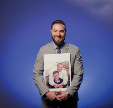 A photograph of Matt Hesketh holding a photo of him and his brother Ben