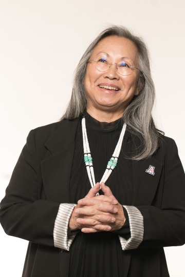A photograph of Irene Ogata, looking up, smiling with her hands together