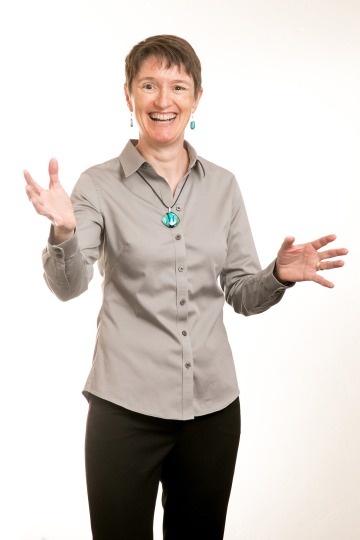 A photograph of Lynn Peyton, smiling with her arms stretched out
