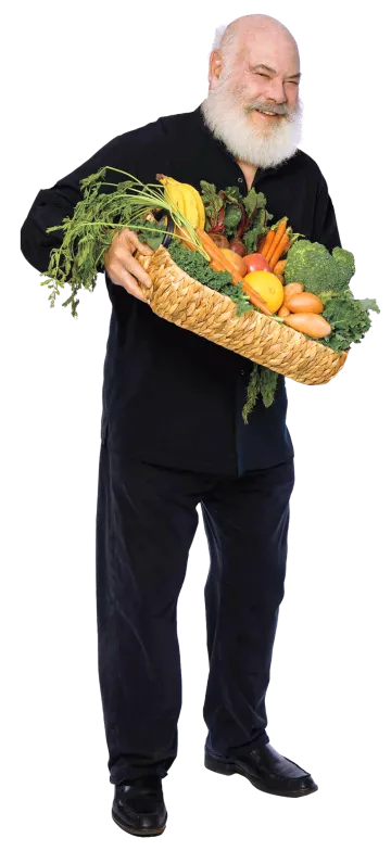 A photograph of Andrew Weil smiling and holding a basket full of fruits and vegetables