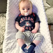 Baby wearing UArizona onesie