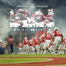 Image of Arizona football team running onto the field at a UA home game