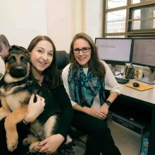 Two researchers pose with Hendrix the German shepherd.