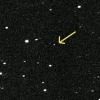 An arrow points to a dot of light among a field of background stars