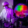 A researcher in a lab coat works on laser technology.