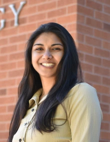A woman standing and smiling in front of a red brick building labeled “Psychology.”
