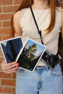 A girl standing with two photograph prints in her hand.